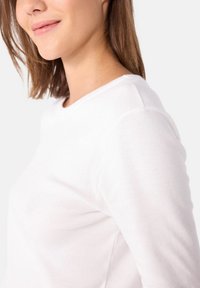 Witte lange mouwen shirt met een ronde hals, gemaakt van zacht materiaal, met een getailleerde snit en minimale naden.