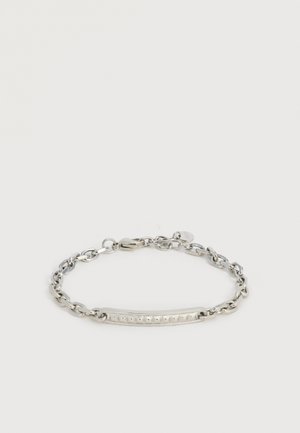 Sølvkædearmbånd med en struktureret, buet søjle som midterstykke og hummerlås på en ens hvid baggrund.