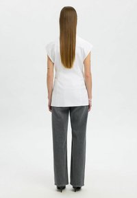 Vit kortärmad blus med rak skärning, tillsammans med högmidjade grå jeans. Slät tyg, enkel design och subtila sömnadsdetaljer.