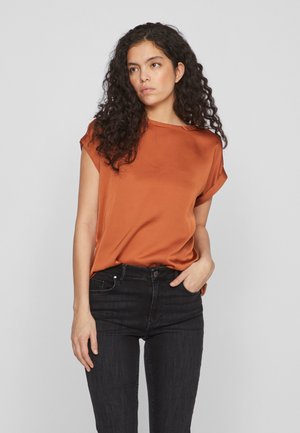 Brændt orange satinbluse med korte ærmer, rund halsudskæring og glat tekstur, parret med sorte jeans.
