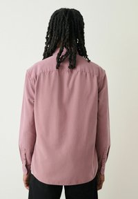 Langärmliges Shirt aus leichter maulbeerenfarbener Baumwolle, mit einem Hemdkragen, sichtbaren Nähten und Knöpfen an den Manschetten, sowie einem geraden Saum.