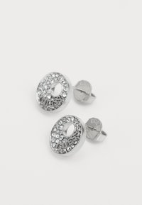 Sølv stud øredobber med sirkulært design, pyntet med strass og en sentral åpning. Merkenavnet er gravert på baksiden.