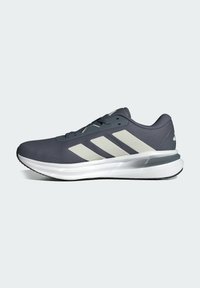 Dark gray athletic shoe with mesh upper, three white stripes, white midsole, rubber outsole, lace-up design, and a padded collar.