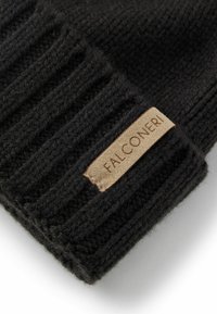 Svart stickad mössa med ribbat mönster, prydd med en beige läderetikett med texten "FALCONERI" präglad på kanten.