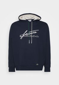 Tmavě modrá mikina s kapucí z bavlny, s šňůrkovou kapucí, přední kapsou a bílým logem se skriptem s malými grafikami krokodýlů.