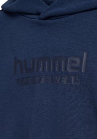 Granatowa bluza z kapturem z teksturowanym, matowym logo "hummel SPORTSWEAR" nadrukowanym w kontrastowym, ciemnym odcieniu z przodu. Drobno tkana tkanina, luźny krój.