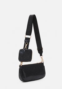 Borsa a tracolla in pelle sintetica nera con hardware dorato, caratterizzata da un motivo logo goffrato e un portacarte staccabile attaccato da una cinghia.