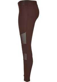 Leggings bruns avec un tissu lisse et des accents en maille sur les côtés. Ils ont une coupe ajustée et une taille haute.