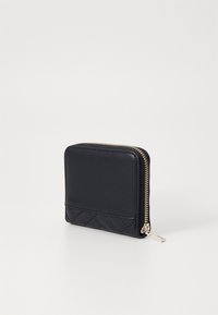 Portefeuille en cuir noir avec un design matelassé texturé d'un côté, présentant une fermeture éclair dorée et une finition lisse de l'autre côté.