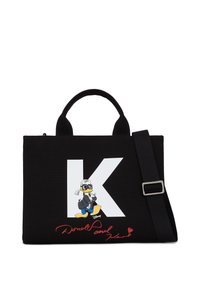 Sac en toile de coton noir avec un grand "K" blanc et un personnage de dessin animé. Comprend des poignées courtes et une bandoulière noire amovible.