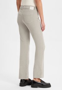 Lichtgrijze rechte broek gemaakt van textiel met twee achterzakken en een label op de tailleband. Gepaarde met zwarte instappers.