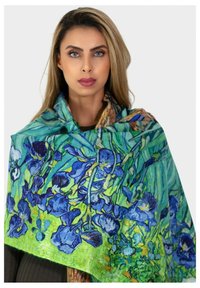 Écharpe florale avec des iris bleus sur un fond vert, fabriquée en tissu léger avec une texture douce, drapée élégamment.