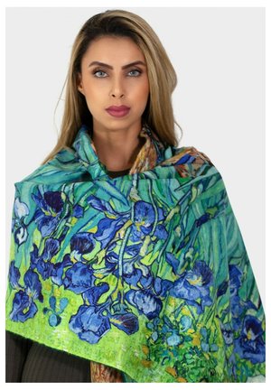 Écharpe florale avec des iris bleus sur un fond vert, fabriquée en tissu léger avec une texture douce, drapée élégamment.