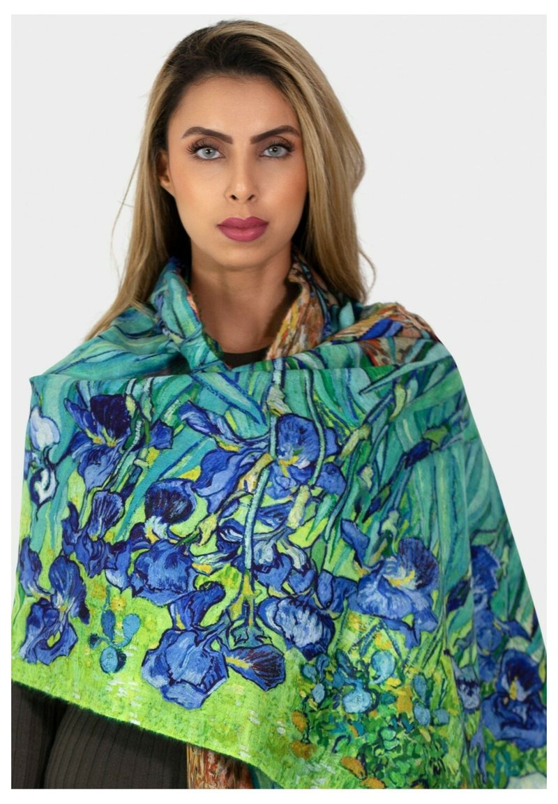 Écharpe florale avec des iris bleus sur un fond vert, fabriquée en tissu léger avec une texture douce, drapée élégamment.