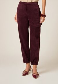 Bordeaux corduroy broek met een ontspannen pasvorm, elastische tailleband, gathered cuffs en zijzakken, gecombineerd met patenten hak schoenen.