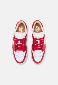 Červené a bílé atletické tenisky s hladkým koženým svrškem, perforovanou špičkou, texturovanými tkaničkami a korkovou stélkou. Viditelné logo Nike.