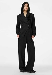 Czarny garnitur w prążki z marynarką zapinaną na jeden guzik i szerokimi spodniami, wykonany z teksturowanej tkaniny, o dopasowanym kroju.