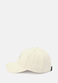 Cremefarvet baseballcap med en buet skygge, justerbar bagside og subtilt broderet tekst på fronten. Stoffet fremstår glat og holdbart.