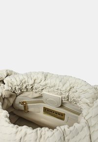Borsa in pelle bianca con un design a pieghe. L'interno presenta una tasca con zip e un'etichetta del marchio. Texture liscia con una forma morbida e flessibile.