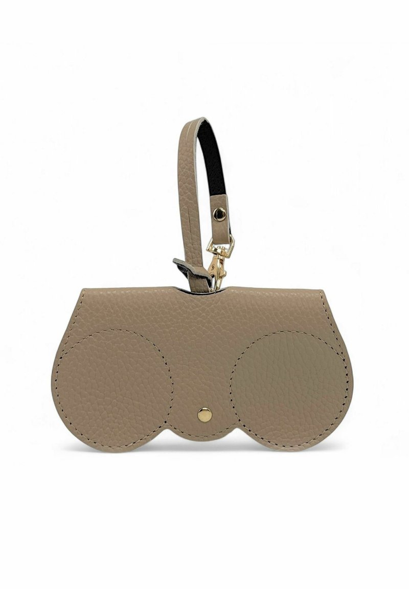 Sac en cuir beige au design arrondi, avec deux accents circulaires, un bouton-pression doré et une bandoulière noire détachable.