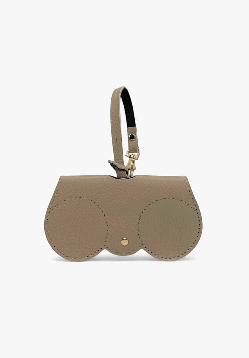 Sac en cuir beige au design arrondi, avec deux accents circulaires, un bouton-pression doré et une bandoulière noire détachable.