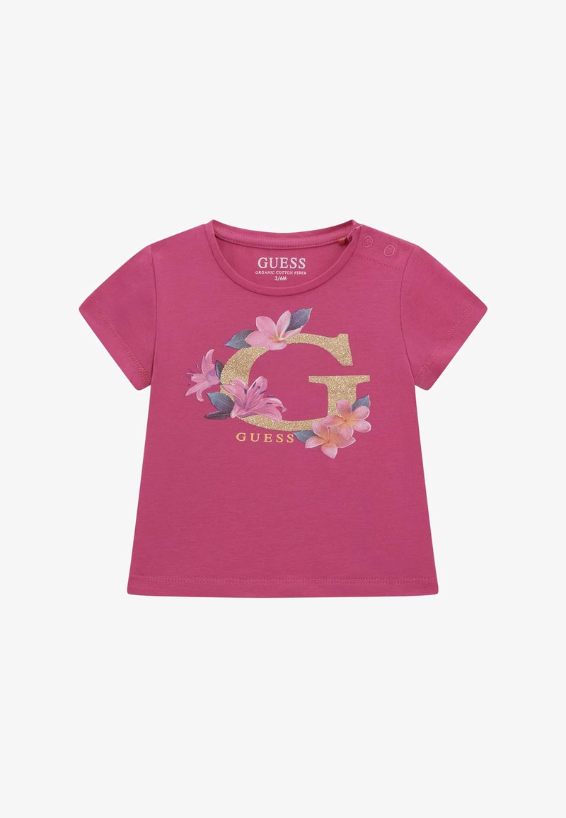 Lyserød T-shirt med korte ærmer lavet af økologisk bomuld, der har et glitrende guld 'G' omgivet af blomster grafik i pink og grøn.