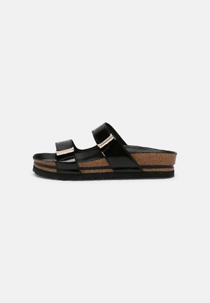Sandale slide noire avec deux brides réglables, semelle plateforme en liège et semelle extérieure en caoutchouc noir texturé sur fond blanc.