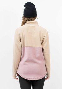 Fleece pullover met een beige bovenkant en een roze onderkant. Beschikt over een kraag en lange mouwen met een gebogen zoom, gemaakt van zachte stof.