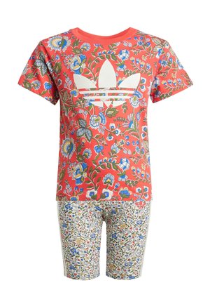 Camiseta roja con estampado floral y logo blanco de Adidas, combinada con pantalones cortos de color claro que presentan un pequeño estampado floral. Material de algodón, mangas cortas.
