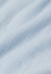 Närbild av ljusblått ribbat tyg med mjuka veck och detaljerad stickad mönster.