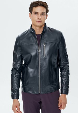Chaqueta de cuero negra para hombre con cuello alto, cierre de cremallera en la parte delantera y bolsillos laterales. Presenta una textura suave y sutiles detalles de costura.
