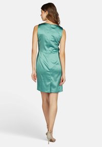 Ein ärmelloses, türkisfarbenes Satin-Kleid mit figurnaher Passform und einem leichten Schwung am Saum sowie einem dezenten Reißverschluss im Rücken.