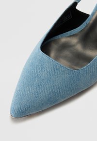 Svetlo modre denim čevlje na peto z koničastim nosom, ki imajo gladko notranjo oblogo in zasnovo z naklonom, ki prikazuje eleganten, sodoben silhuet.