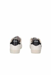 Sneakers bianchi con un accento nero sul tallone, realizzati in materiale liscio, dotati di una suola in gomma bianca e un minimo dettaglio del logo sul retro.