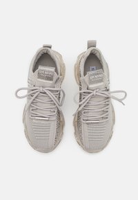 Hellgraue Sneakers mit Mesh-Details, Schnürung und dekorativen Akzenten. Sie verfügen über eine gepolsterte Sohle und ein Markenetikett an der Zunge.