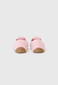 Zapatillas de fieltro rosa sin cordones con forma redondeada, que presentan una textura suave y suela de goma para mayor agarre. Diseñadas con un aspecto sencillo y minimalista.