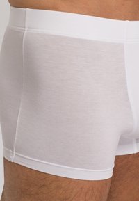Vita bomull boxershorts med en slät yta, med låg midja och kontrasterande sömmar längs sidorna och midjebandet.