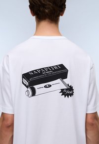 Hvid bomulds T-shirt med et grafisk print på ryggen af et rør med teksten: "NAPAPIJRI SO FRESH! Anbefalet af fagfolk."