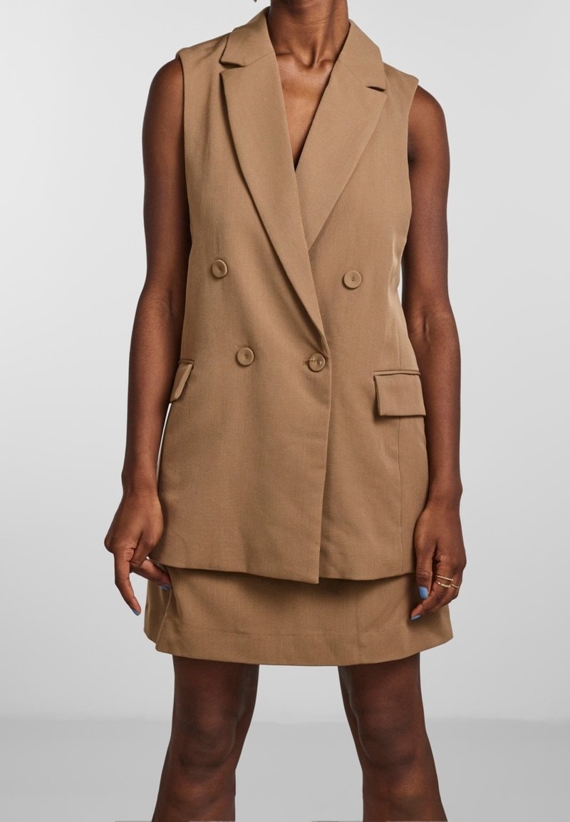 Hnědý dvouřadý bezrukávový blejzr s klopami, dvěma předními kapsami a přiléhavým střihem, doplněný o odpovídající mini sukni.