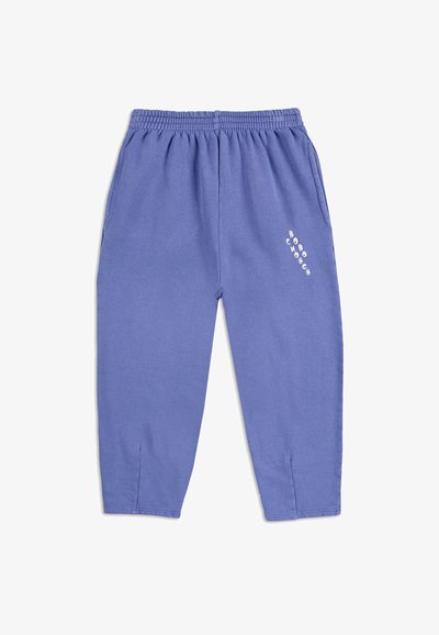 Sudadera de color púrpura claro con cintura elástica, bolsillos laterales y detalle de texto blanco en la parte inferior de la pierna derecha. Tela suave y texturizada.