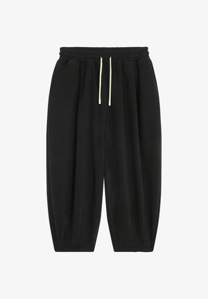Pantalons de survêtement noirs à coupe ample, avec une taille élastique et des cordons de serrage de couleur claire. Comprend des poches latérales et une texture de tissu douce.