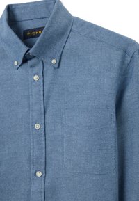 Camicia azzurro chiaro in cotone con bottoni, colletto appuntito, taschino sul petto e texture sottile a spina di pesce. Bottoni bianchi classici.