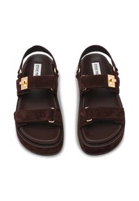 Donkerbruine suède sandalen met twee brede bandjes, goudkleurige hardware en een ronde teen ontwerp met een verhoogde platte zool.