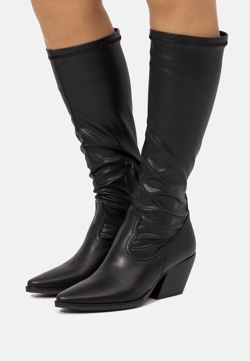 Botas altas de cuero negro con un diseño arrugado, punta puntiaguda y tacón bloque moderado. Cuenta con cremallera lateral y parte superior texturizada.