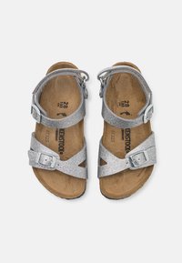 Sandali argentati glitter con cinturini regolabili e fibbie metalliche. Suola in sughero con interno in pelle marrone chiaro. Taglia segnata come 28.