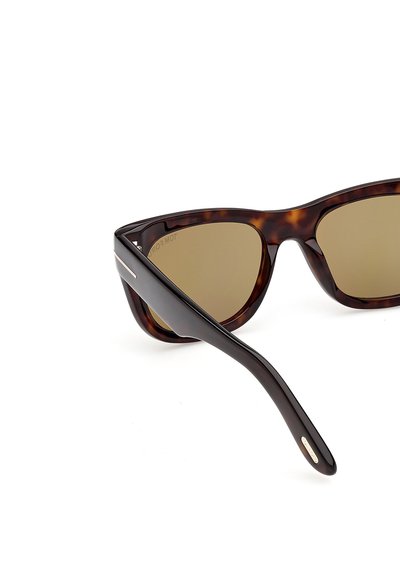 Tortoiseshell sunglasses with thick frames and brown tinted lenses, featuring a small metal detail on the temple arm.