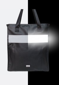 Zwarte tote bag gemaakt van duurzaam materiaal, met een reflecterende strook in het midden, dubbele handvatten en een logo-tag aan de onderkant.