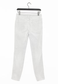 Jeans de denim gris claro colgados de una percha negra, con un corte recto, diseño de cinco bolsillos y detalles de costura minimalistas.