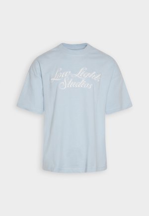 Lys blå bomuld t-shirt med korte ærmer og rund hals. Har hvid broderet tekst "Low Lights Studios" på forsiden.