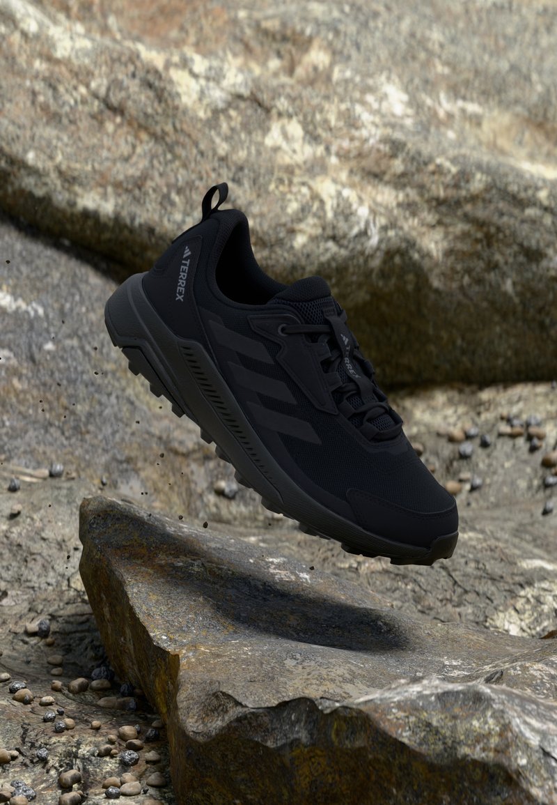 Schwarzer Sportschuh mit Mesh-Obermaterial, Gummisohle und strukturierten Akzentlinien. Verfügt über eine verstärkte Zehen- und Ösenpartie. Leichtes Design.